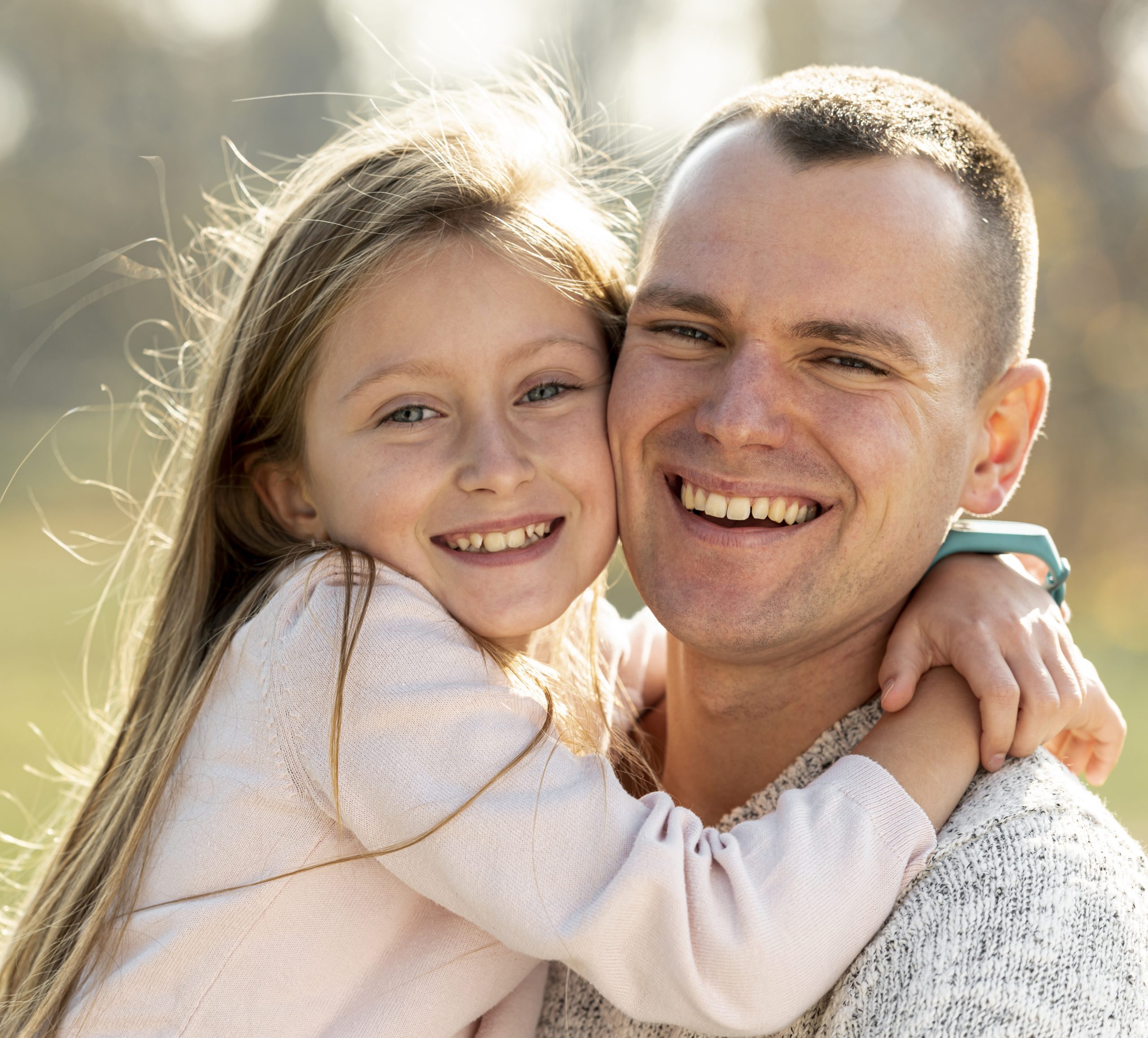 A smiling middle aged dad with his happy young daughter in his arms