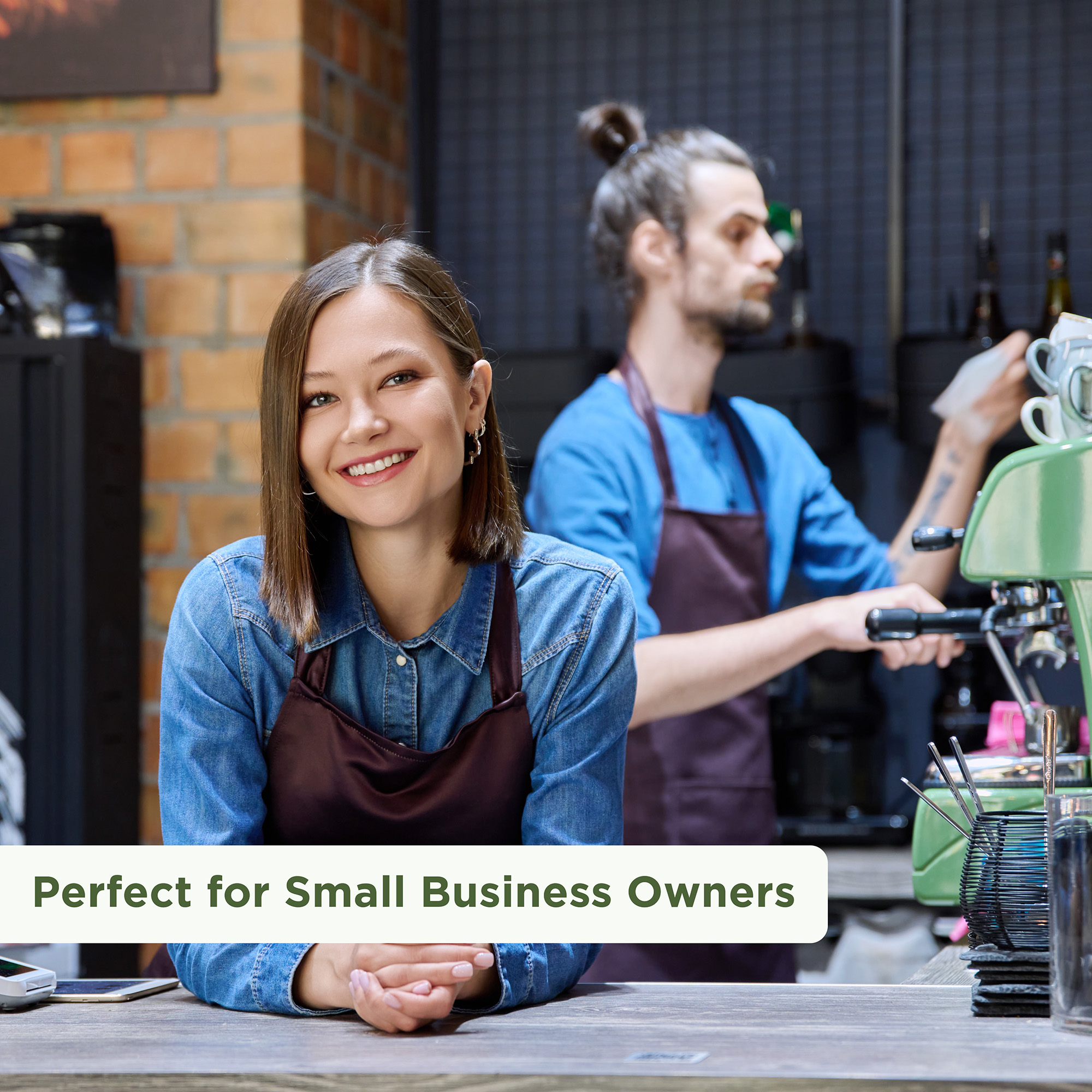 A friendly woman in a coffee shop leaning on the counter with a barista behind her making coffee